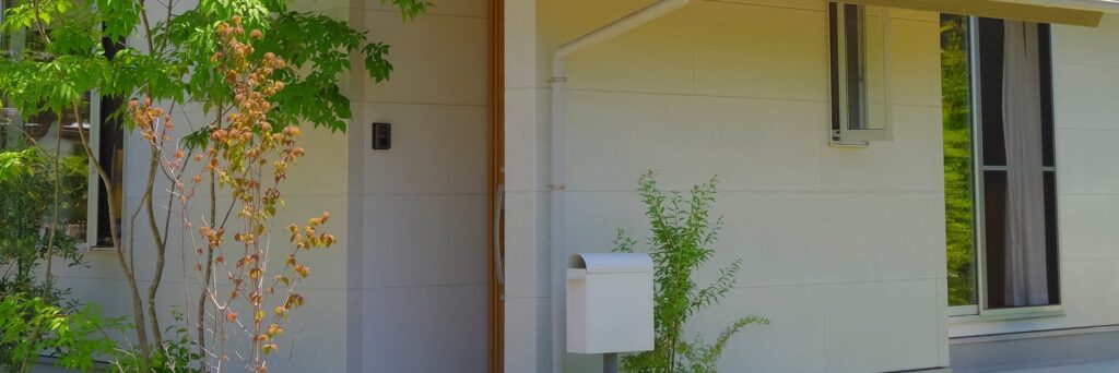 木製ドアと郵便受けが並ぶ、やわらかな玄関まわり
